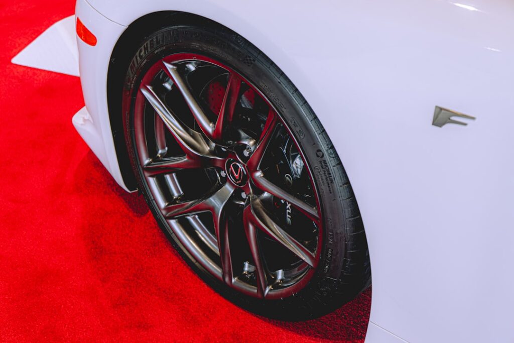White car wheel and fender on a vibrant red carpet.